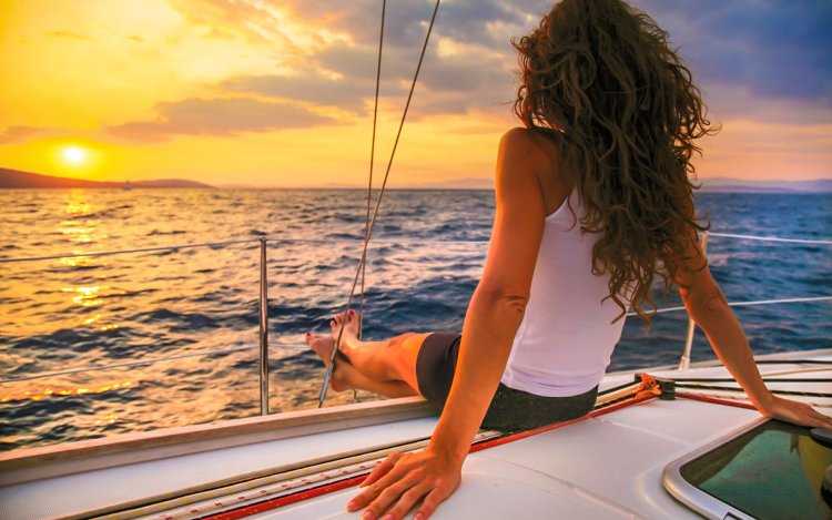 Девушка у моря со спины и парусник