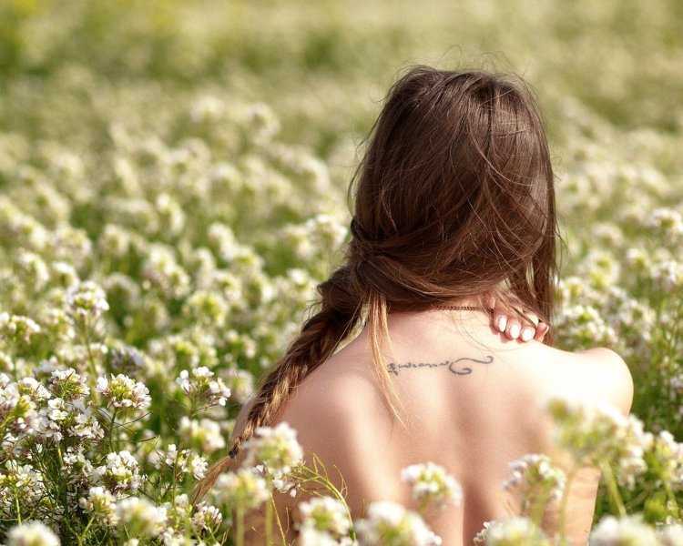 Девушка в поле с цветами со спины