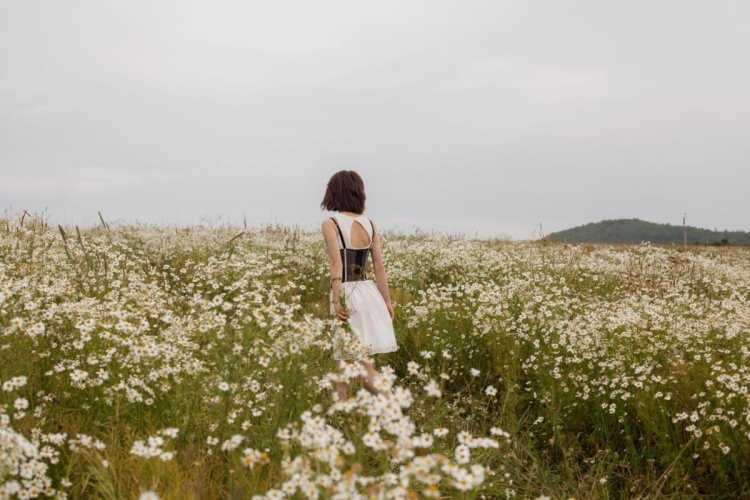 Девушка в ромашковом поле со спины