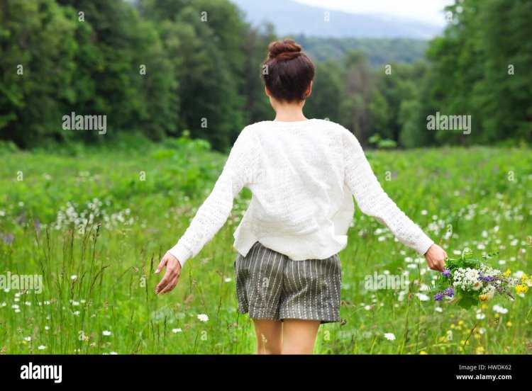 Девушка в поле с ромашками со спины