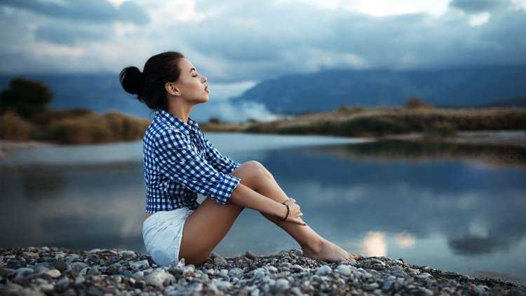 Девушка сидит на берегу