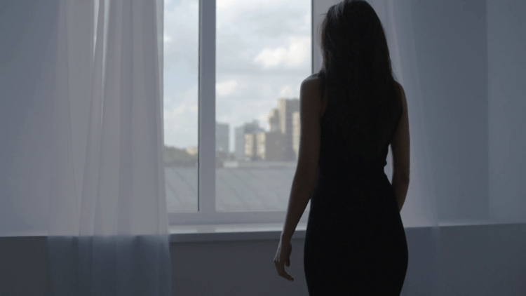 Вид девушки сзади у окна в платье
