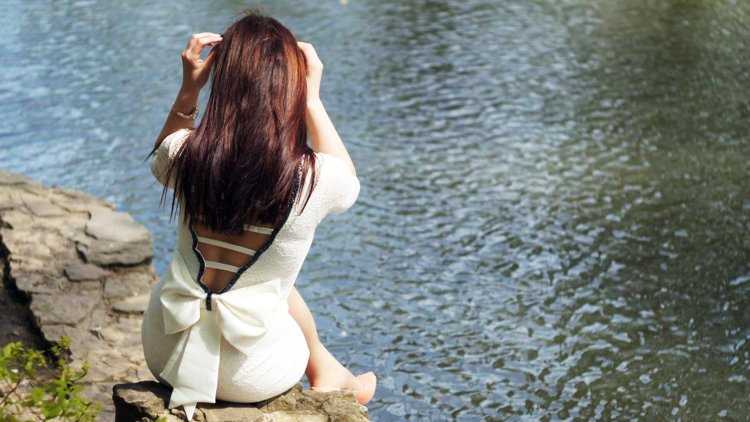 Девушка у реки со спины