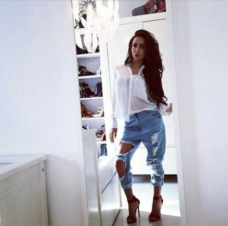 Девушка брюнетка в рваных джинсах