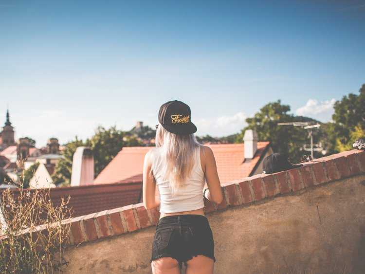 Пленительная девушка в спортивной бейсболке приковывает взгляд со спины