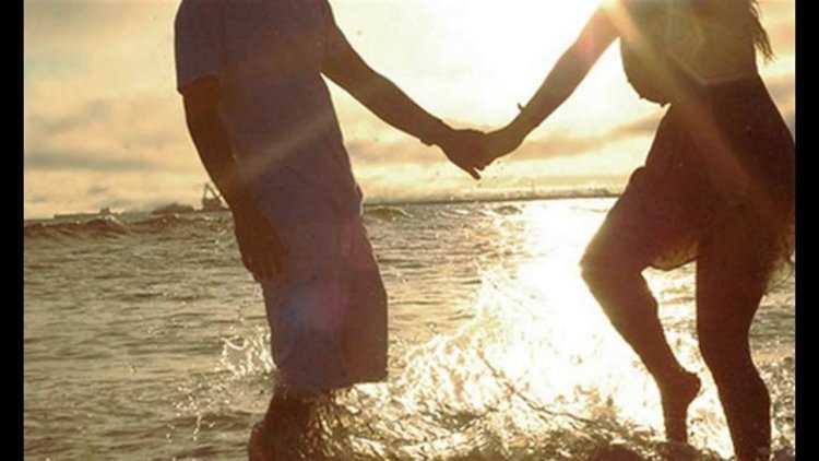 Парень с девушкой на пляже со спины