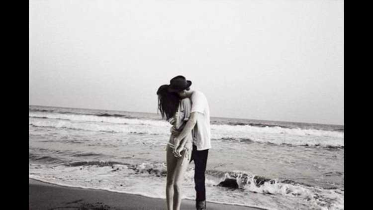 Обнимает девушку на море