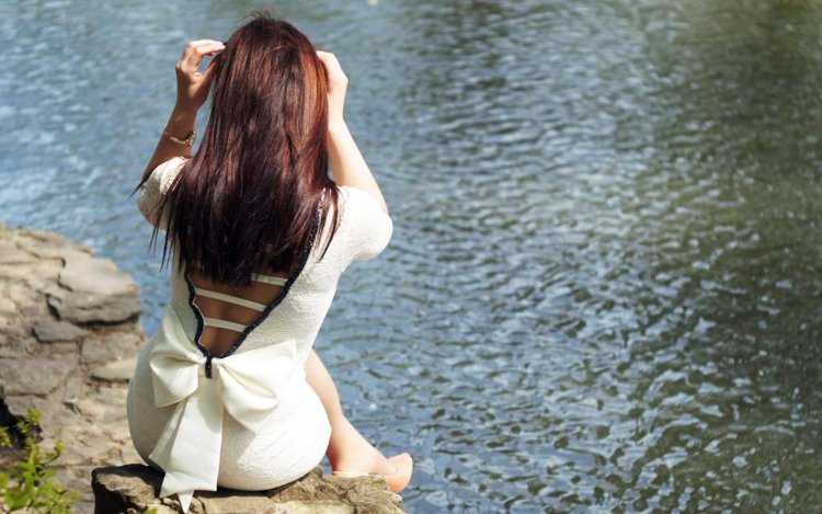 Девушка у реки со спины