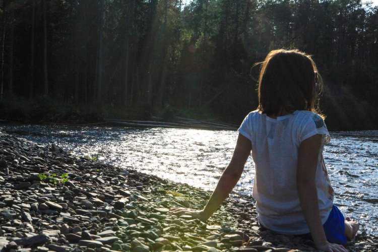 Девушка у реки со спины