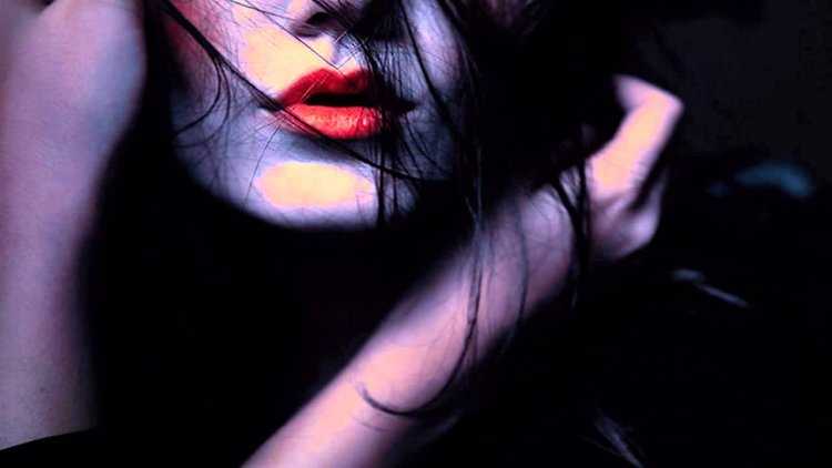 Девушка с красными губами в темноте