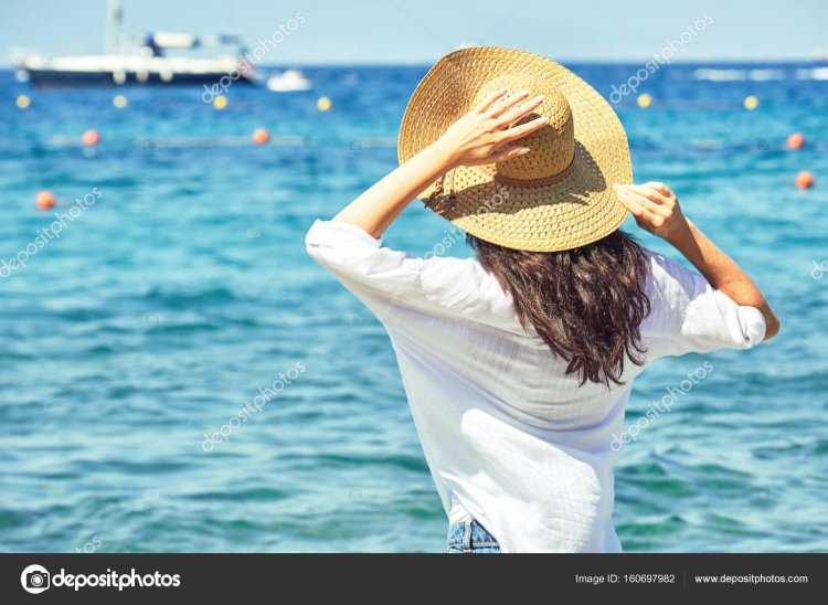 Женщина в шляпе со спины на море