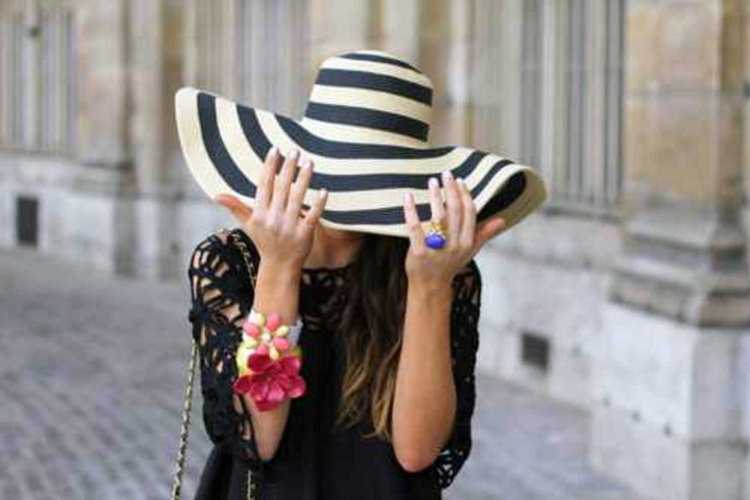 Девушка в шляпе прикрывает лицо руками