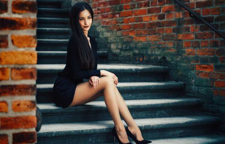 Брюнетка в черном платье сидит