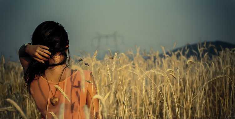 Брюнетка в поле со спины