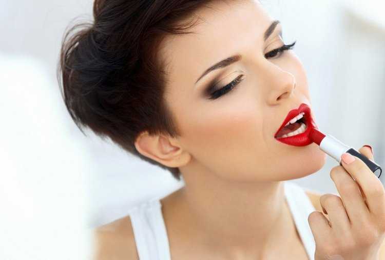 Женщина красит губы красной помадой