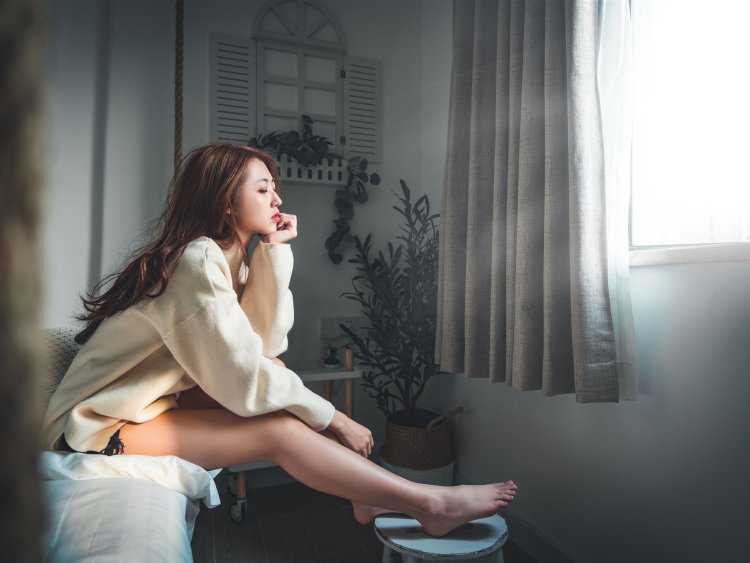 Соблазнительная девушка, расслабленно сидящая на подоконнике