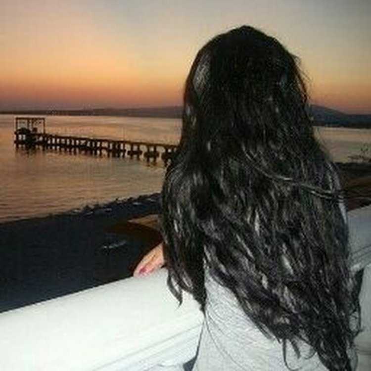 Брюнетка с длинными волосами, играющая со своим телом у моря