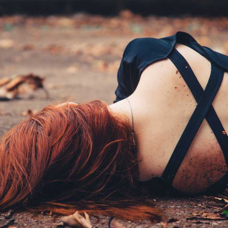 Рыжеволосая девушка в черном со спины