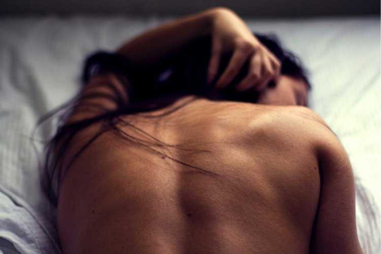 Брюнетка со спины на кровати