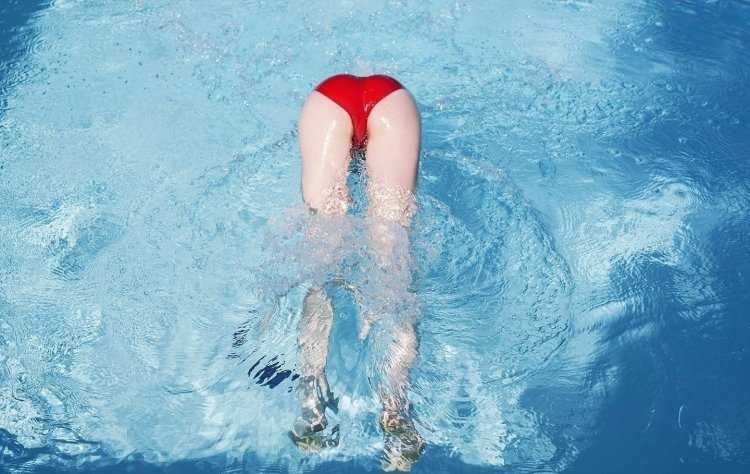 Девушка ныряет в бассейн